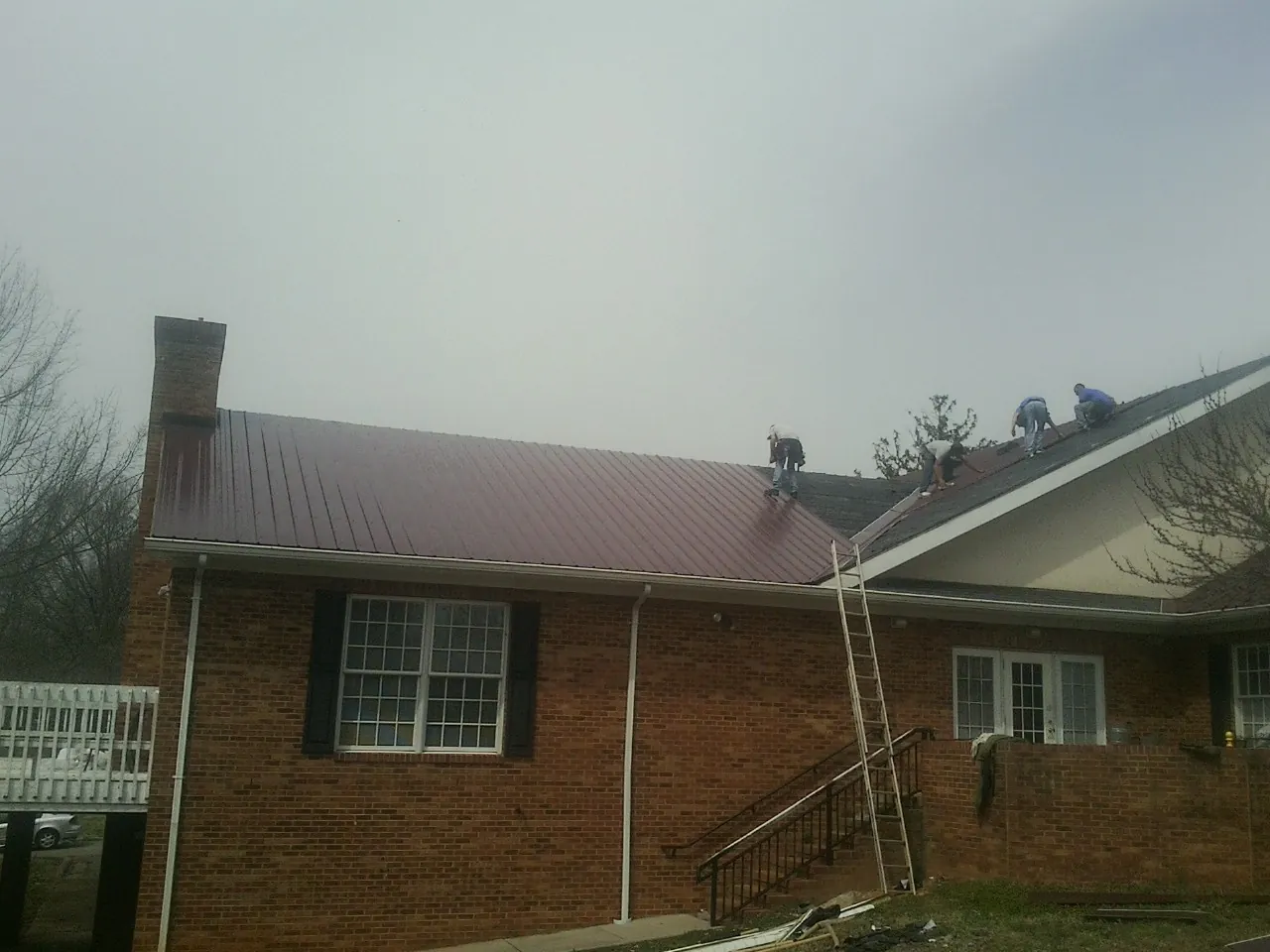 Crew setting red metal roofing panels on a brick home in Florence
